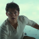 Tom Holland's Nathan Drake wears a long-sleeved white shirt and stands before an open sky.